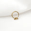 A gold-colored ring with a small bat-shaped charm is placed on a white fabric surface.