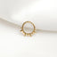 A gold-colored ring with spikes protruding from it, resting on a white fabric surface.