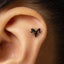 A close-up of a person's ear with a small black horn-shaped earring attached to the side of the ear.