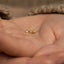 a person holding a tiny gold ring in their hands