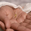 A person's hand holding a small gold-colored turtle charm.
