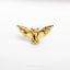 a gold bat pin sitting on top of a white surface
