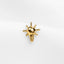 a gold bee brooch sitting on top of a white surface