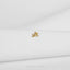 A small gold-colored rabbit charm is resting on a white fabric surface.