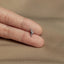 a person's hand holding a tiny silver bow ring
