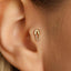 A gold-colored earring with a safety pin attached to it is visible in the image.
