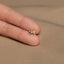 a person's hand holding a tiny gold bow ring