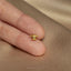 a person's hand holding a tiny gold ring