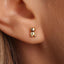 A small gold-colored earring in the shape of a teddy bear is visible in the image.