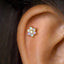 A gold-colored earring with a flower-shaped design and small stones is visible in the image.