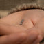 a person's hand with a tiny ring on it
