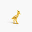A small golden bird figurine is standing on one leg against a white background.