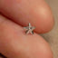 a person's hand holding a tiny silver star ring