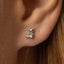A silver earring in the shape of a cat is visible in the person's ear.