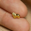 A small, shiny gold lion figurine is being held between two fingers.