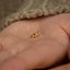 a person's hand holding a tiny gold bird ring