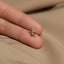a person's hand holding a tiny gold ring