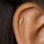 A close-up of a person's ear with a small gold-colored push pin stud in the earlobe.