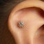 A close-up view of a person's ear, showing a small, silver stud or piercing in the earlobe.