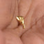 A close-up image of a person's hand holding a small, gold-colored object, which appears to be a piece of jewelry.
