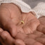 A close-up image of a person's hand holding a small gold-colored object, possibly a piece of jewelry.
