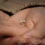 a woman's hand holding a tiny gold ring