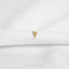 A single gold earring is resting on a white fabric surface.