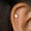 A gold-colored earring with a hand-shaped design is visible in the image.