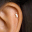 A gold-colored earring in the shape of a kangaroo is visible in the image.