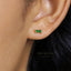 A close-up of a person's ear with a small green gemstone earring.