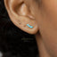 A close-up of a person's ear with a small blue gemstone earring.