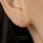 A close-up of a person's ear with a small gold triangle-shaped earring.
