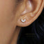 A close-up of a person's ear wearing a small, delicate earring with a small, clear gemstone.