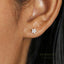 A close-up of a person's ear with a small, delicate earring featuring a flower-shaped design.