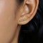 A close-up of a person's ear with a gold-colored earring inserted.