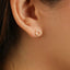 A close-up view of a person's ear, showing a small gold-colored earring with a circular design.