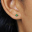 A close-up of a person's ear with a small, green gemstone earring.