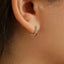 A close-up view of a person's ear with a small gold-colored earring attached.