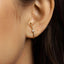 A close-up view of a person's ear, showing a gold earring with a small diamond accent.