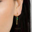 A close-up of a person's ear wearing a gold earring with a green gemstone.