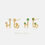 a pair of gold earrings with gemstones, including green and white stones, and a twisted design.