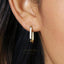 A close-up view of a person's ear wearing a gold-colored hoop earring.