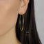 A close-up of a person's ear wearing a gold hoop earring.