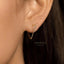 A close-up of a person's ear with a gold-colored earring in the shape of a triangle.