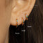 A close-up of a person's ear with three colorful earrings, each measuring 6mm in length.