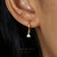 A close-up view of a person's ear adorned with a gold hoop earring featuring a small diamond.