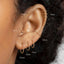 a close-up view of a person's ear with multiple gold hoop earrings. The earrings are labeled with their sizes in millimeters, ranging from 6 to 12.