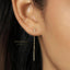 A close-up of a person's ear wearing a pair of gold earrings with a crescent moon charm hanging from the chain.