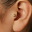 A gold-colored earring with a small crab-shaped charm is visible in the ear.