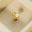 A small gold bunny charm is placed on a beige surface.